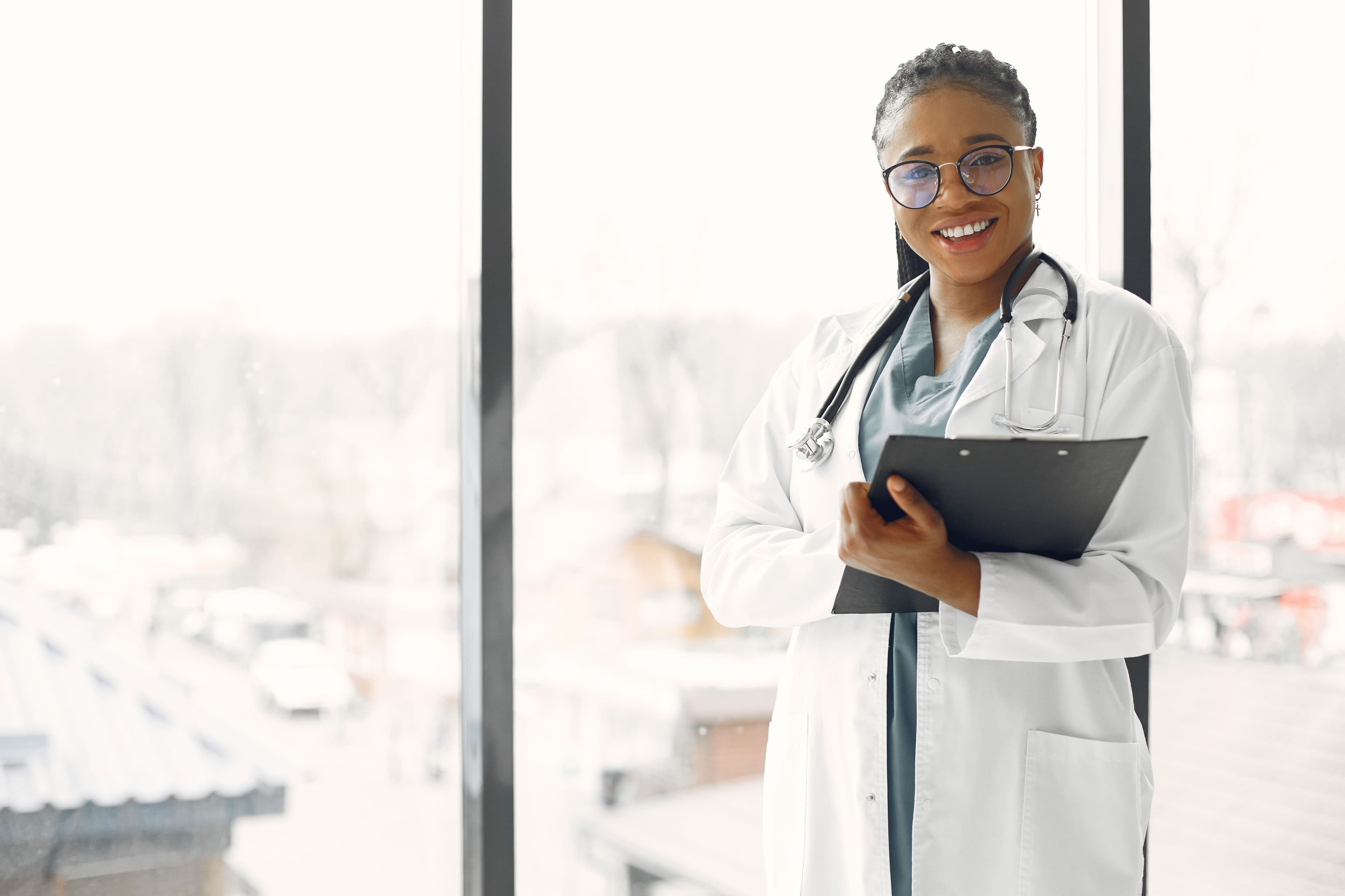 Smiling clinician in a white coat holding a clipboard
