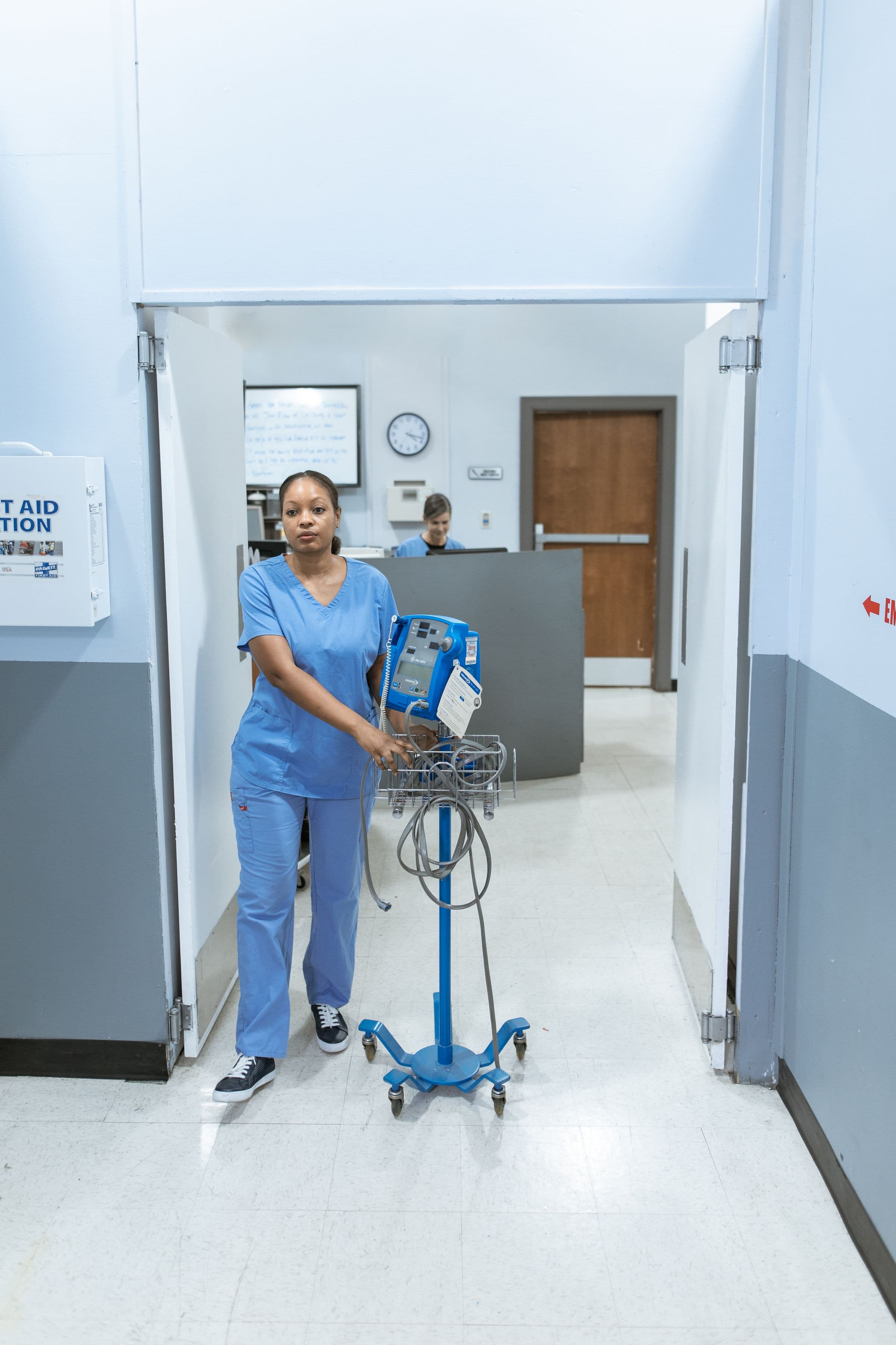Nurse moving clinical equipment through a hospital corridor